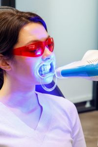 A young woman receives a teeth whitening procedure at a dental clinic.